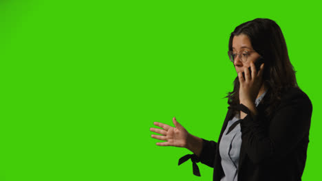 Frustrated-Young-Businesswoman-Wearing-Glasses-Talking-On-Mobile-Phone-Against-Green-Screen-Studio-Background-2